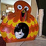 animal, black_and_white, box, cardboard_house, cat, chicken_shape, colorful, cozy, cute, eyes, face, floor_tile, funny, furniture, home, indoor, living_room, pet, playful, scratching_post