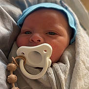 Cameron joined the competition — help win amazing prizes! baby, pacifier, blue_cap, blanket, onesie, beaded_clip, face, sleepy, cozy, infant, soft_texture, zipped_onesie, wrapped, indoor, closeup, newborn, child, cute, resting, warm