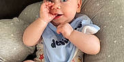 Thomas is registered to the contest to win money with this photo: baby, infant, child, cushion, pillow, onesie, bib, hand, thumb_sucking, blue_eyes, skin, cute, comfort, indoor, person, clothing, relaxing, sitting, expression, face