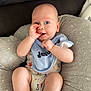 baby, infant, child, cushion, pillow, onesie, bib, hand, thumb_sucking, blue_eyes, skin, cute, comfort, indoor, person, clothing, relaxing, sitting, expression, face