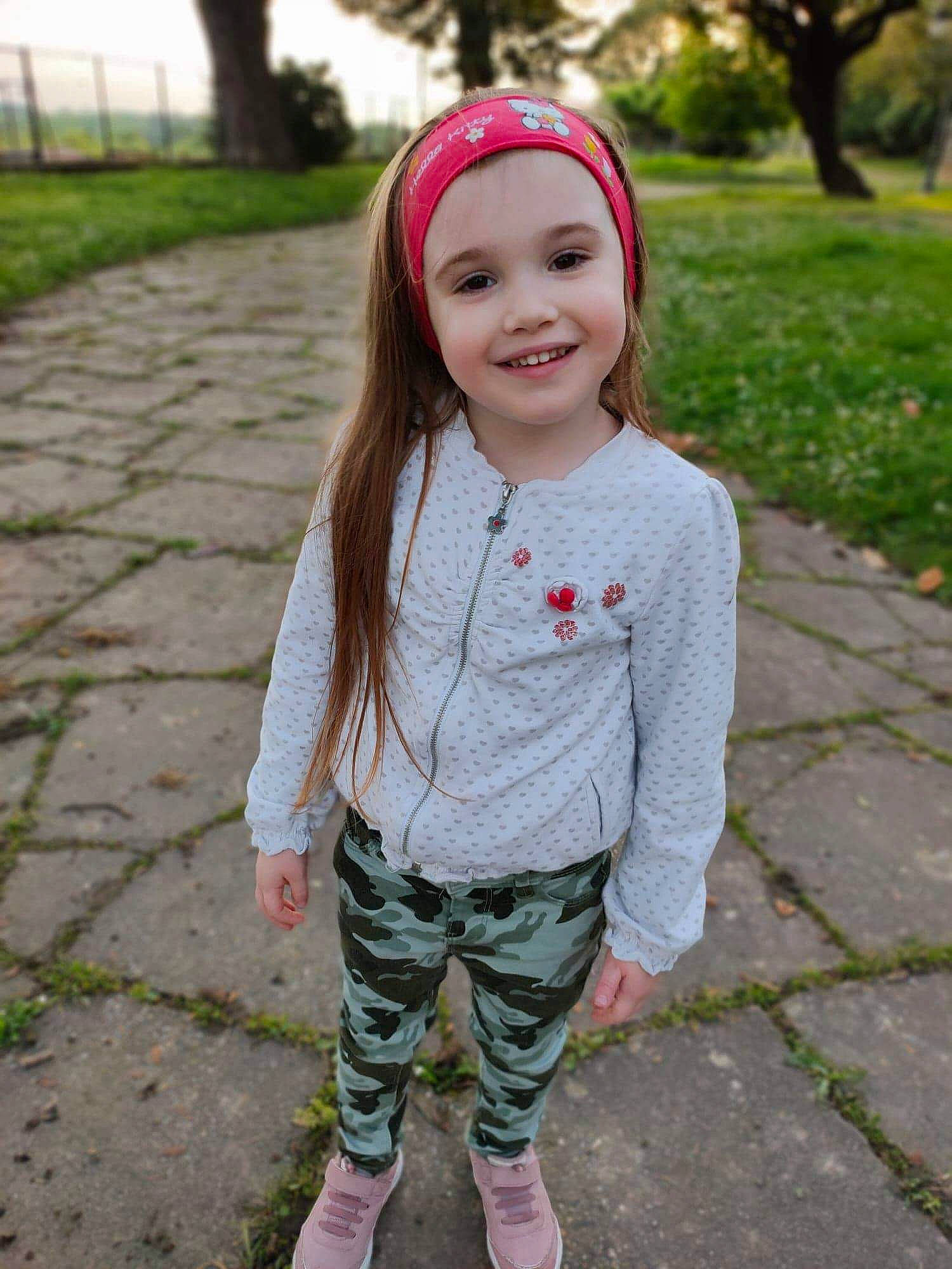 Tatiana participe au concours pour gagner de l'argent avec cette photo : child, child_model, clothing, face, grass, hair_accessory, head, headband, headgear, headwear, joy, leggings, lip, outerwear, pattern, person, photography, pink, sleeve, smile