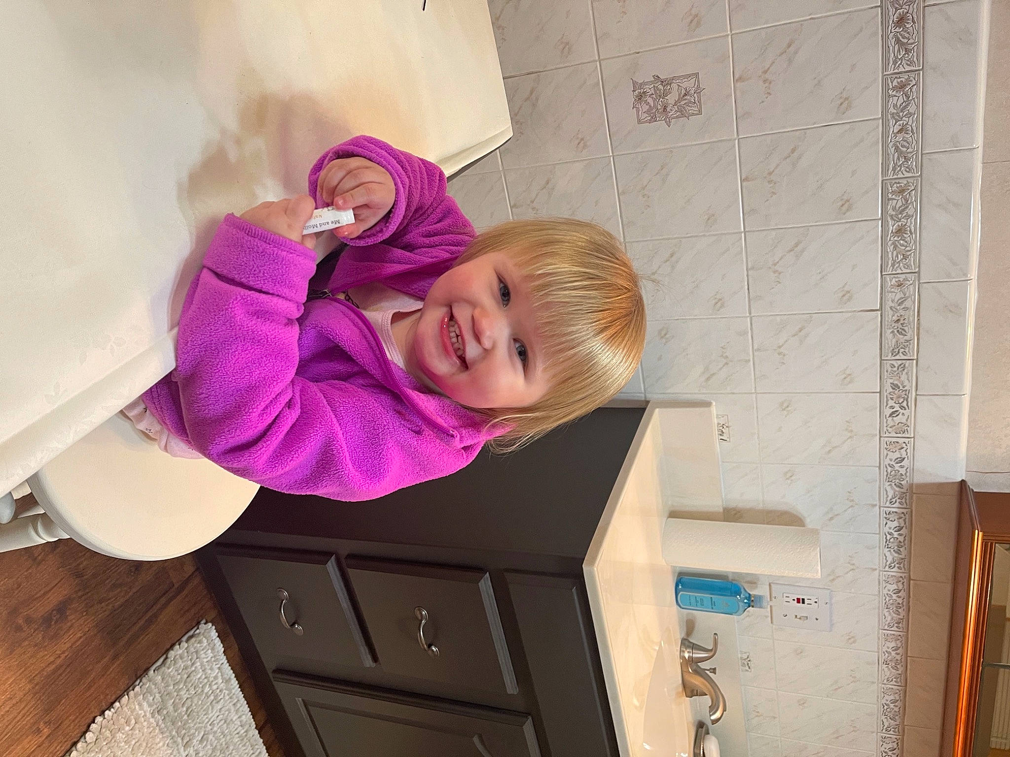 Malia Mae is registered to the contest to win money with this photo: baby_toddler_clothing, cabinetry, chest_of_drawers, child, comfort, drawer, dresser, floor, flooring, glasses, happy, hardwood, interior_design, joy, magenta, material_property, person, pink, purple, smile