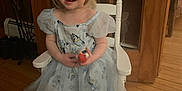 Emilena Joy is registered to the contest to win money with this photo: child, smiling, dress, bluey, toy, white_chair, barefoot, wooden_floor, indoor, blonde_hair, short_hair, puffy_sleeves, glass_door, wood_paneling, happy, person, seated, home_interior, cute, girl