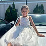 child, girl, white_dress, car, outdoor, smiling, sunlight, pearl_beads, happy, portrait, vehicle, trees, shoes, fashion, cute, summer, daylight, person, parked_car, accessory