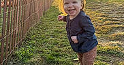 Briella Skye is registered to the contest to win money with this photo: child, toddler, smiling, outdoor, sunset, fence, grass, happy, hair, clothing, shoes, nature, daylight, person, portrait, cute, sunlight, field, playful, young