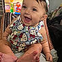 baby, smiling, child, infant, headband, clothing, hello_kitty, sitting, feet, toes, indoors, television, cartoon, colorful, happy, person, cute, expression, closeup, playful