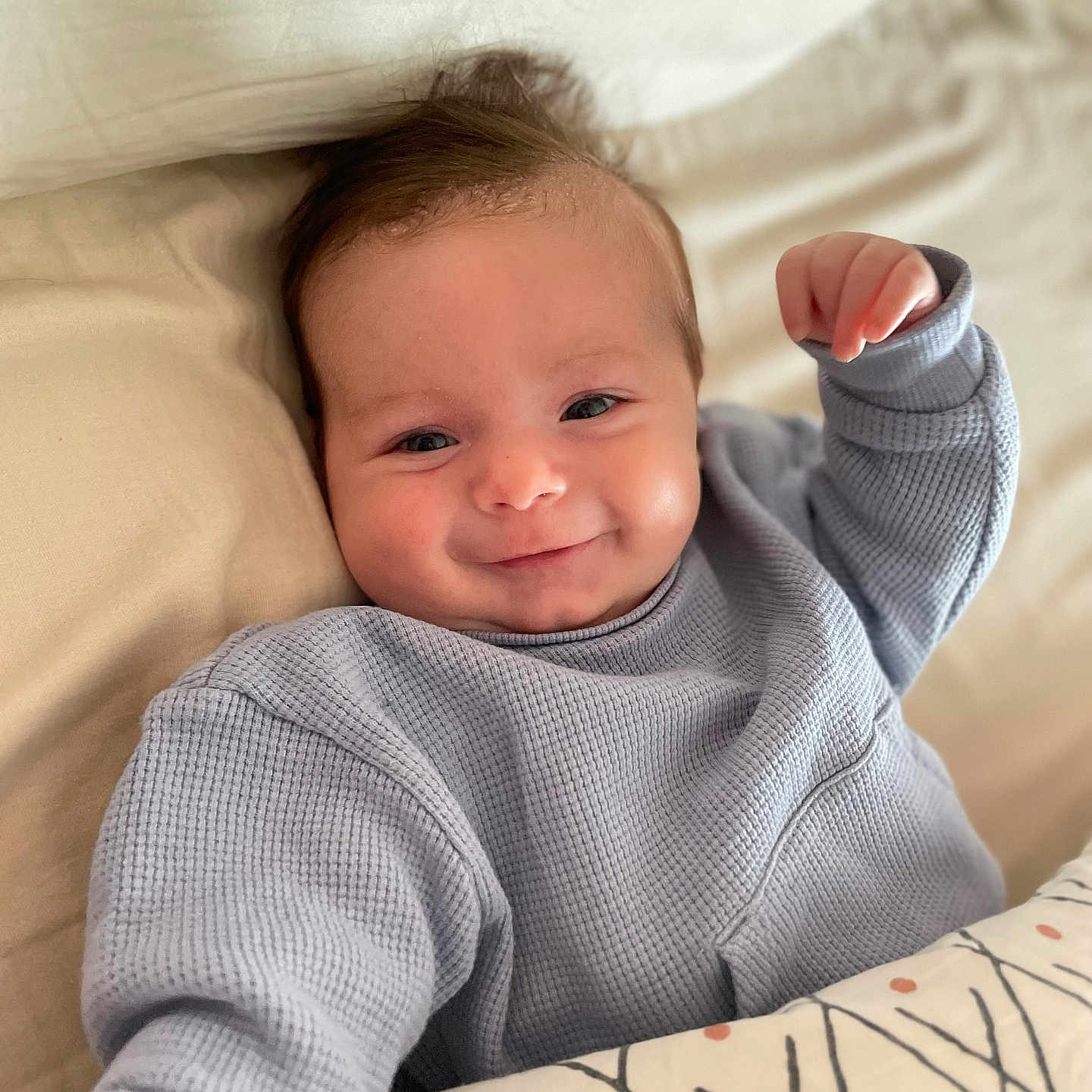 Malo a rejoint le concours — aidez-le/la à gagner de superbes lots ! baby, smiling, blue_sweater, blanket, bed, infant, person, face, happy, cute, child, lying_down, cozy, indoors, soft_light, patterned_blanket, hand, young_child, portrait, warm