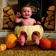 Bonnie is registered to the contest to win money with this photo: baby, pumpkin, white_pumpkin, orange_pumpkin, floor, carved_pumpkin, fireplace, firewood, wood, wallpaper, baby_smiling, child, indoors, cute, happy, legs, toes, seasonal, autumn, decor