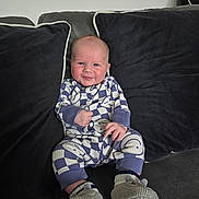 Matthew joined the competition — help win amazing prizes! baby, child, couch, pillow, smile, onesie, knitted_booties, indoor, seated, cute, infant, face, person, cozy, relaxed, home, furniture, soft, comfort, patterned_clothing