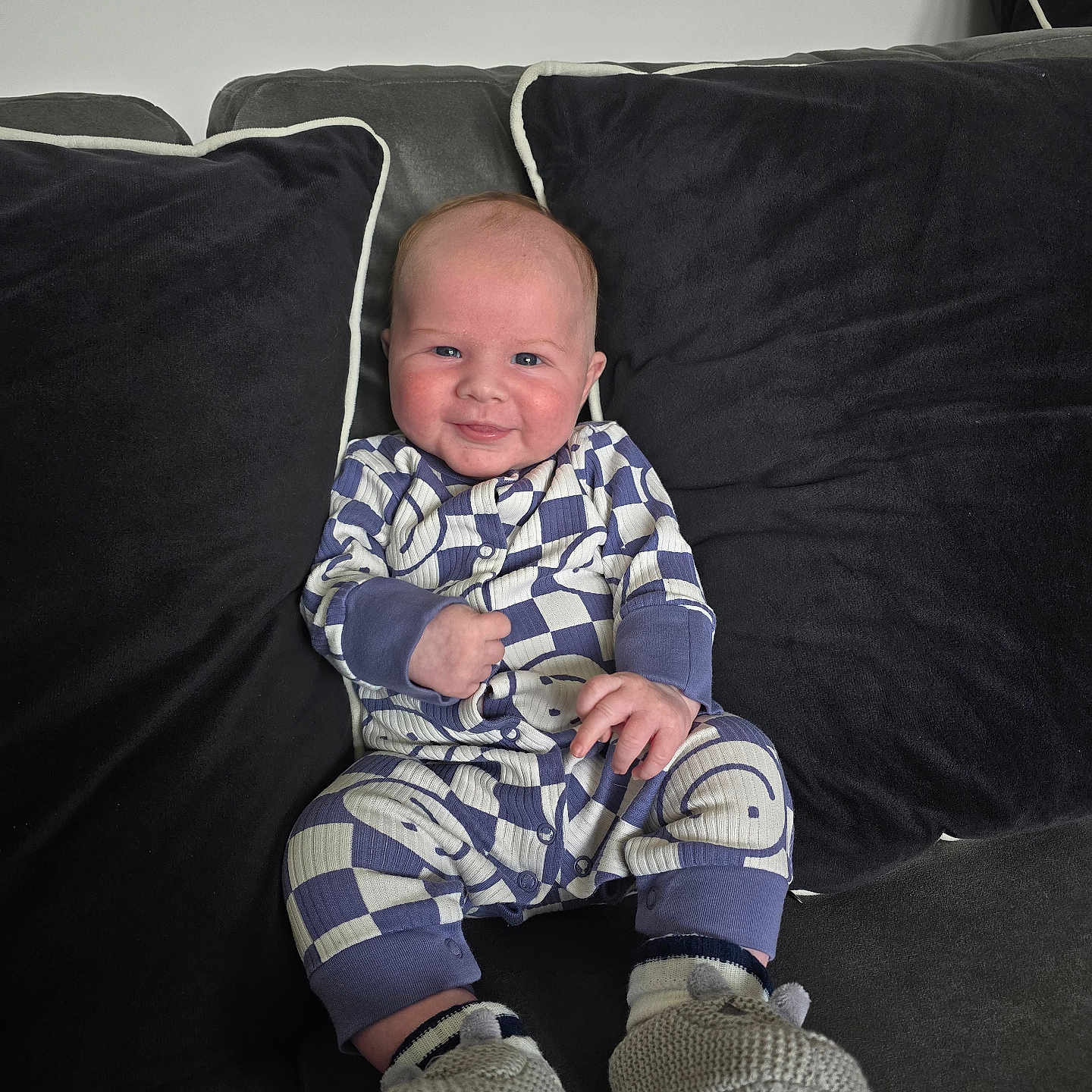 Matthew joined the competition — help win amazing prizes! baby, child, comfort, couch, cozy, cute, face, furniture, home, indoor, infant, knitted_booties, onesie, patterned_clothing, person, pillow, relaxed, seated, smile, soft