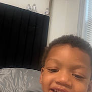 Truu is registered to the contest to win money with this photo: bed, bedroom, blinds, casual, child, closeup, curly_hair, face, happy, headboard, indoor, light, person, portrait, relaxed, skin, smile, water_bottle, window, young_child