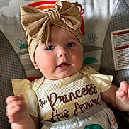 Charlotte is registered to the contest to win money with this photo: baby, infant, headband, bow, clothing, smile, face, cute, child, sitting, seat, pattern, sun, indoor, apparel, person, portrait, toddler, expression, colorful