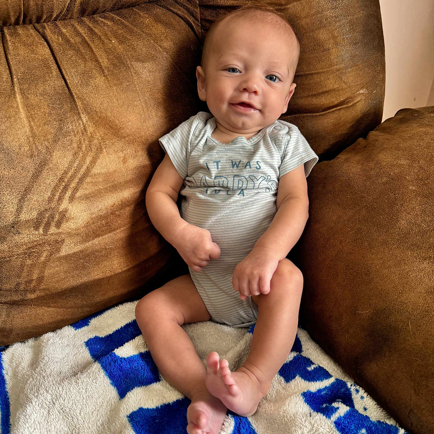 Creed is registered to the contest to win money with this photo: baby, blanket, blue, brown, child, clothing, comfortable, couch, foot, hand, happy, head, indoor, infant, person, relaxed, sitting, skin, smiling, white