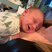 Rylan is registered to the contest to win money with this photo: baby, newborn, infant, sleeping, smiling, onesie, tree_print, chest, shoulder, hair, skin, nursery, baby_bottle, blanket, pillow, closeup, cozy, portrait, indoor, caregiver