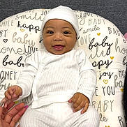 Mykel joined the competition — help win amazing prizes! baby, child, closeup, comfort, cozy, cushion, cute, expression, hand, happy, hat, human, indoors, infant, joyful, playful, portrait, smiling, text_pattern, white_clothing