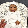 baby, child, closeup, comfort, cozy, cushion, cute, expression, hand, happy, hat, human, indoors, infant, joyful, playful, portrait, smiling, text_pattern, white_clothing