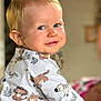 animal_print, baby, blond_hair, blue_eyes, child, clothing, cute, face, happy, head, indoor, looking_back, person, playful, portrait, sitting, skin, smiling, toddler, young_child