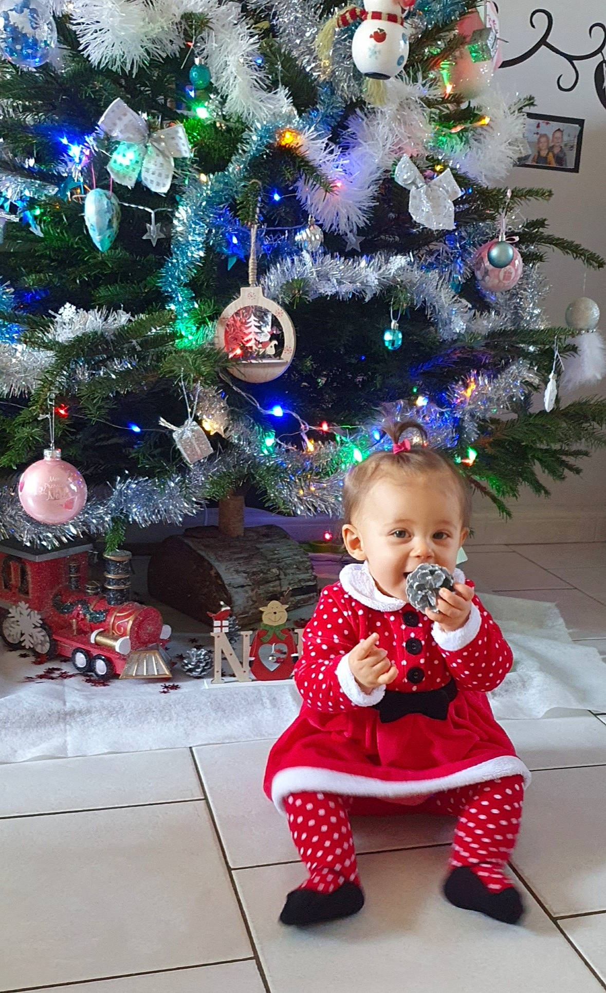 Maëlya a rejoint le concours — aidez-le/la à gagner de superbes lots ! baby, baby_toddler_clothing, child, christmas, christmas_decoration, christmas_eve, christmas_lights, christmas_ornament, christmas_tree, conifer, event, evergreen, holiday, holiday_ornament, human, interior_design, ornament, person, pine_family, toddler