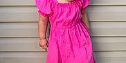 Elaine joined the competition — help win amazing prizes! toddler, child, pink_dress, white_sandals, curly_hair, smiling, outdoor, wooden_floor, siding, happy, portrait, cute, standing, young_child, playful, fashion, feet, person, summer, innocence