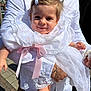 Elya participe au concours pour gagner de l'argent avec cette photo : baby, child, smile, white_dress, lace, ribbon, bow, person, adult, hand, outdoor, sunlight, portrait, face, clothing, fabric, cute, holding, happy, fashion