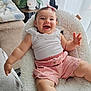 baby, bow_headband, casual_clothing, child, couch, curtains, cute, fluffy_chair, happy, home, indoor, infant, pink_shorts, plant, portrait, pot, relaxed, smiling, waving_hand, white_top