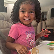 Nami joined the competition — help win amazing prizes! child, couch, curly_hair, cute, food, fruit, hand, happy, high_chair, indoor, living_room, mealtime, person, pink_shirt, portrait, smiling, sofa, table, toddler, watermelon