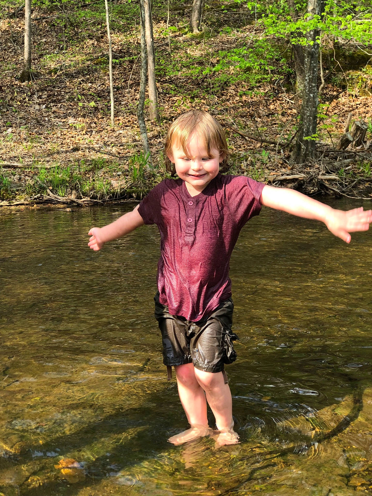 Arianna is registered to the contest to win money with this photo: bank, barefoot, body_of_water, creek, forest, fun, grass, happy, joy, lake, leisure, mammal, people_in_nature, person, plant, smile, stream, toddler, vertebrate, water