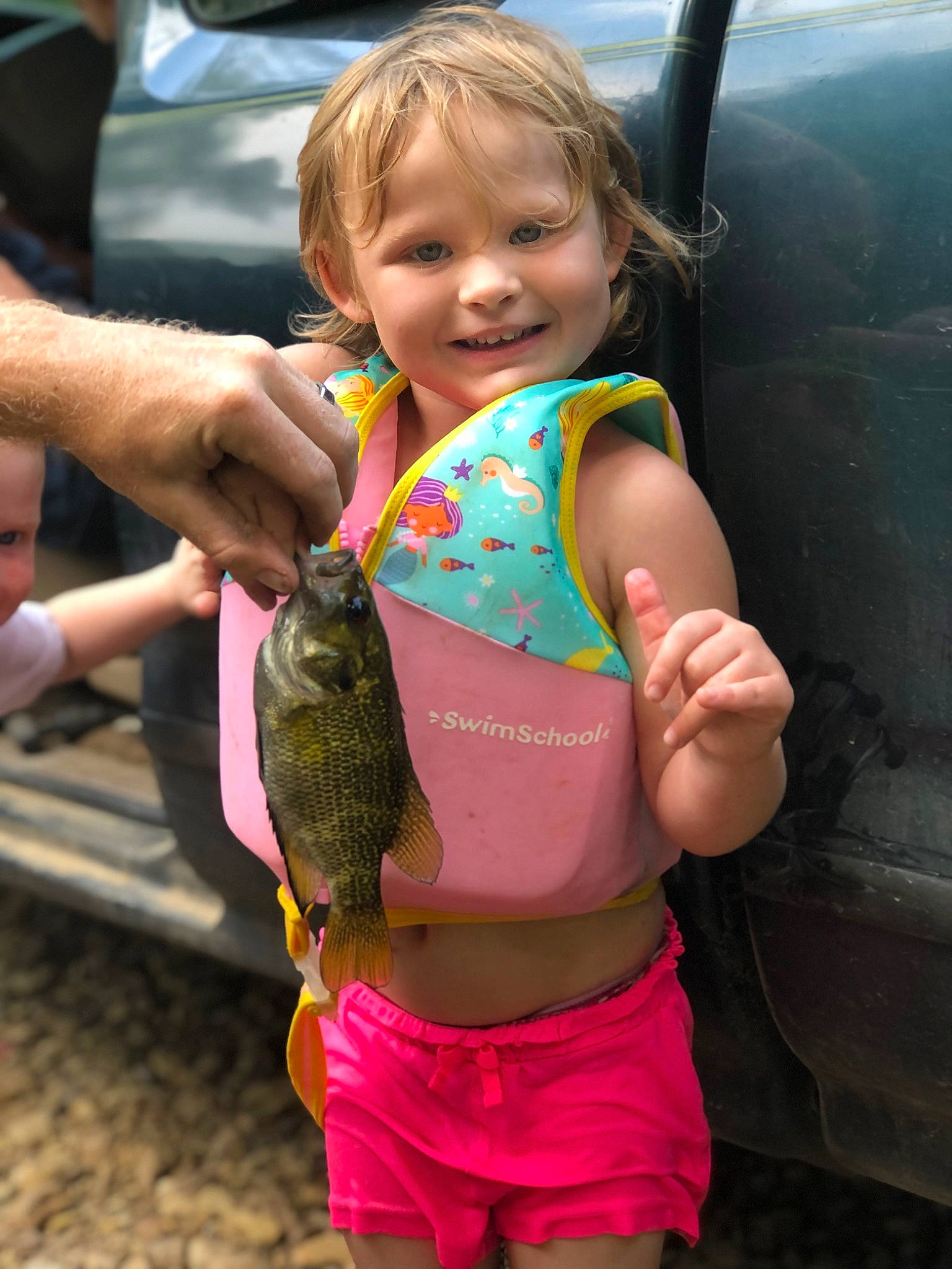 Arianna is registered to the contest to win money with this photo: child, finger, fish, fisherman, fishing, fun, grass, happy, human_leg, joy, leisure, person, pink, ray_finned_fish, recreation, shorts, skin, smile, summer, thumb