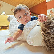 Thiago a rejoint le concours — aidez-le/la à gagner de superbes lots ! baby, child, blue_eyes, stuffed_animal, plush_toy, indoor, wooden_ceiling, carpet, curious, cute, person, toddler, soft_toy, smiling, hand, face, crawling, home, cozy, childhood