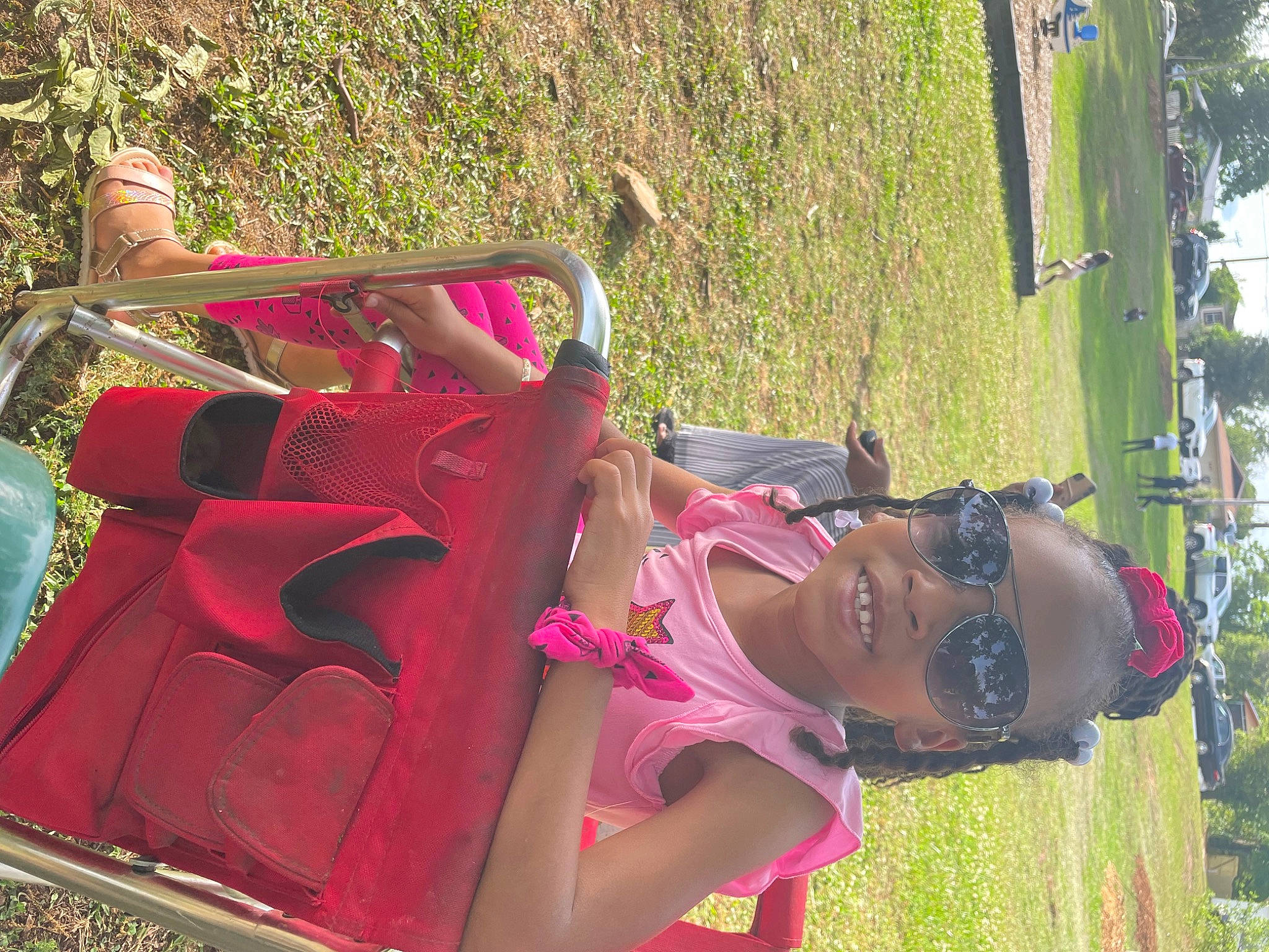 Kimora is registered to the contest to win money with this photo: botany, chair, dress, fun, grass, leaf, leisure, luggage_and_bags, magenta, outdoor_furniture, outdoor_play_equipment, people_in_nature, person, pink, plant, recreation, red, shoulder_bag, sitting, sunglasses