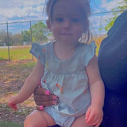 Adalynn joined the competition — help win amazing prizes! toddler, child, outdoor, sky, tree, grass, person, hand, fence, nails, blue_clothing, baby, legs, face, sitting, daylight, nature, holding, curly_hair, portrait