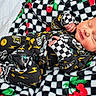 Sutton joined the competition — help win amazing prizes! newborn, baby, sleeping, blanket, checkered_pattern, cherry_pattern, black_clothing, yellow_smiley, lightning_bolt, infant, cute, peaceful, cozy, soft_texture, hand, feet, portrait, indoors, resting, child