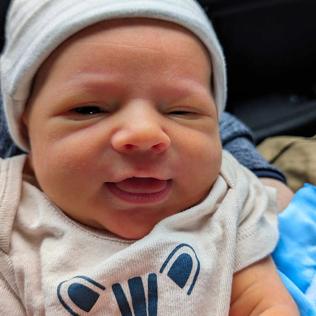 Weston is registered to the contest to win money with this photo: baby, beanie, bodypart, bonnet, cap, clothing, face, finger, glove, hand, happy, hat, head, hoodie, knitwear, newborn, person, photography, portrait, smile