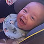 baby, smiling, car_seat, bib, child, infant, happy, seatbelt, face, clothing, cute, young, head, person, indoors, seat, safety, transportation, expression, joyful