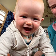 Theo joined the competition — help win amazing prizes! baby, child, smiling, indoor, hoodie, person, face, candid, happy, young_child, adult, home, closeup, casual_clothing, human_hand, furniture, light, skin, expression, joy