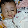 Maura is registered to the contest to win money with this photo: baby, child, smiling, blanket, elephant_pattern, hand, cushion, floral_pattern, clothing, indoor, sleepy, cute, happy, person, infant, resting, toddler, closeup, face, skin