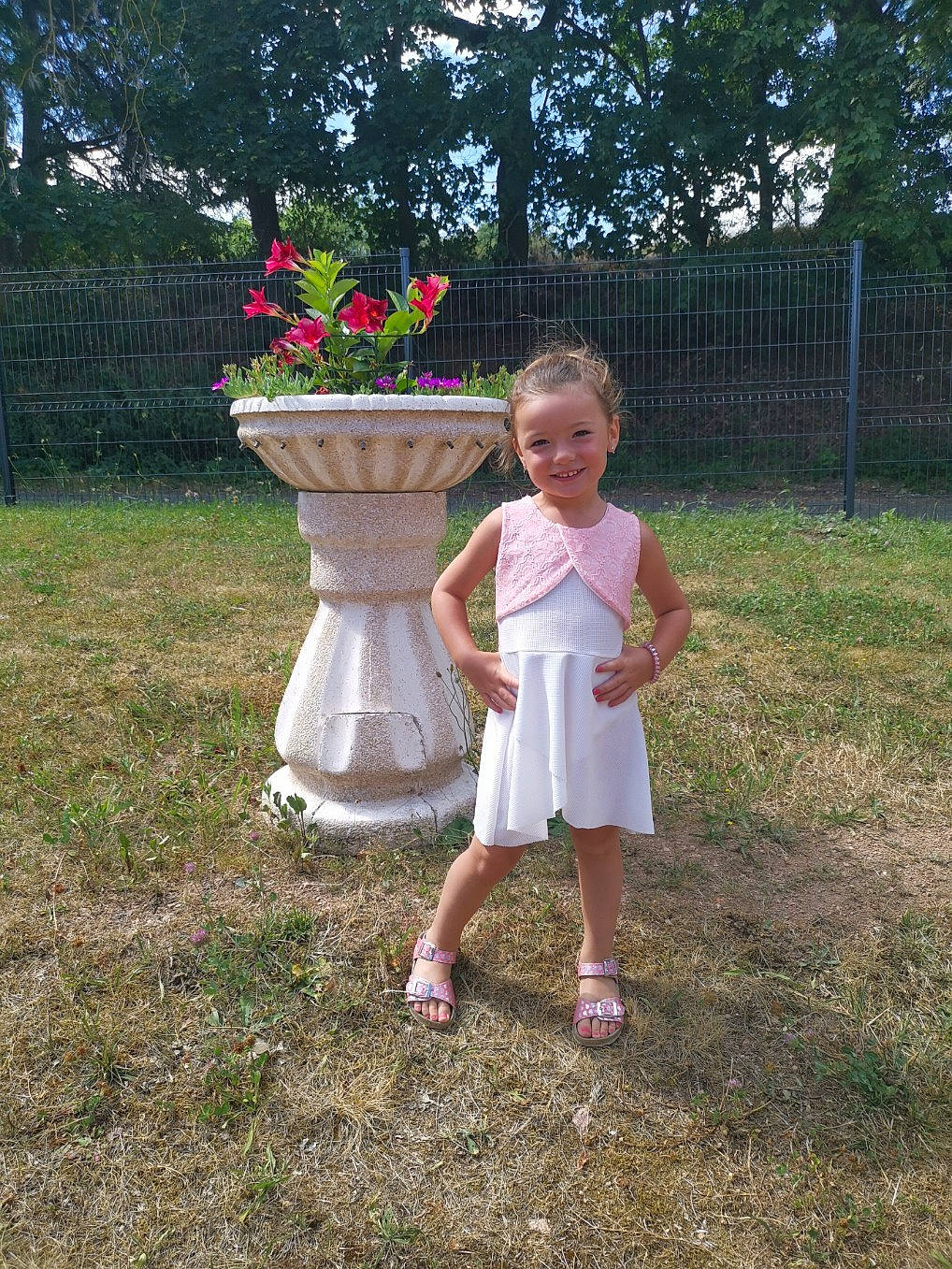 Romy a rejoint le concours — aidez-le/la à gagner de superbes lots ! annual_plant, baby_toddler_clothing, backyard, child, day_dress, dress, fence, flowerpot, foot, garden, joy, magenta, one_piece_garment, person, petal, pink, sandal, shrub, spring, summer
