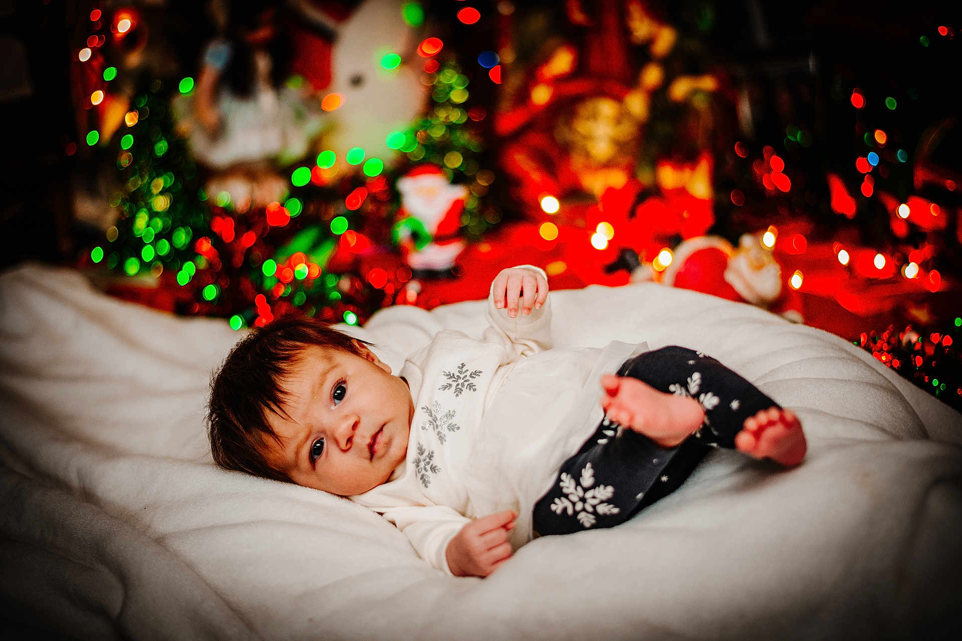 Annalee joined the competition — help win amazing prizes! baby, infant, blanket, clothing, christmas_lights, holiday, festive, decorations, soft, lying_down, indoors, cozy, face, person, cute, winter, snowflake_pattern, warm, colorful, blurred_background