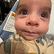 Theodore joined the competition — help win amazing prizes! baby, infant, face, eyes, onesie, clothing, closeup, child, seat, warning_label, fabric, pattern, smile, skin, young, cute, indoors, person, portrait, baby_seat