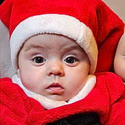 Mya participe au concours pour gagner de l'argent avec cette photo : baby, child, face, portrait, red_clothing, santa_hat, holiday, costume, cute, infant, expression, eyes, closeup, christmas, festive, warm_clothing, indoors, person, headwear, soft_texture