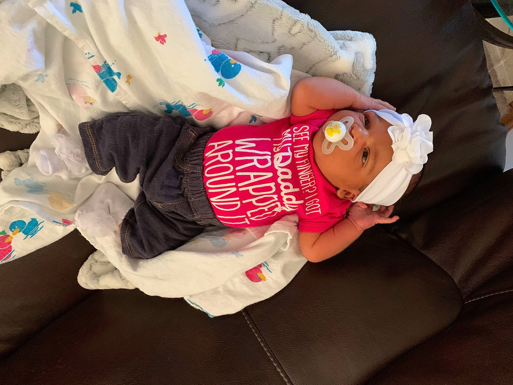 Kennedie is registered to the contest to win money with this photo: abdomen, arm, baby, baby_carriage, baby_products, baby_toddler_clothing, child, comfort, elbow, event, glasses, hat, headgear, headwear, human_leg, pattern, person, sitting, sleeve, t_shirt