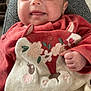 baby, smiling, infant, child, red_clothing, embroidered_clothing, animal_design, cute, cozy, happy, indoors, portrait, face, hand, fist, soft_texture, warm, person, closeup, young_child