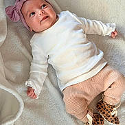 Camélia participe au concours pour gagner de l'argent avec cette photo : baby, infant, child, headband, bow, white_shirt, ribbed_clothing, pants, peach_color, leopard_print, booties, blanket, soft_texture, smiling, lying_down, cute, portrait, indoors, happy, person