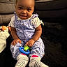 toddler, child, smiling, indoor, plush_toy, couch, black_rug, striped_socks, floral_jumpsuit, pigtails, toy, cute, happy, person, seated, home, cozy, portrait, baby, playful