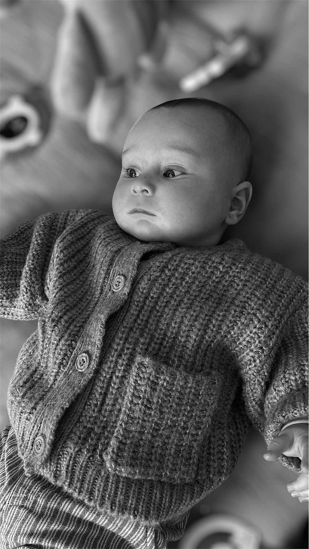 Léon participe au concours pour gagner de l'argent avec cette photo : baby, infant, knitwear, cardigan, portrait, face, child, cozy, soft_lighting, black_and_white, clothing, texture, hand, expression, blurred_background, indoors, cute, young, newborn, peaceful