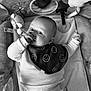 baby, bib, blanket, child, closeup, clothing, comfort, curious, cute, face, indoor, infant, lying_down, monochrome, person, play_area, smile, soft_toys, star_toy, thumb_sucking