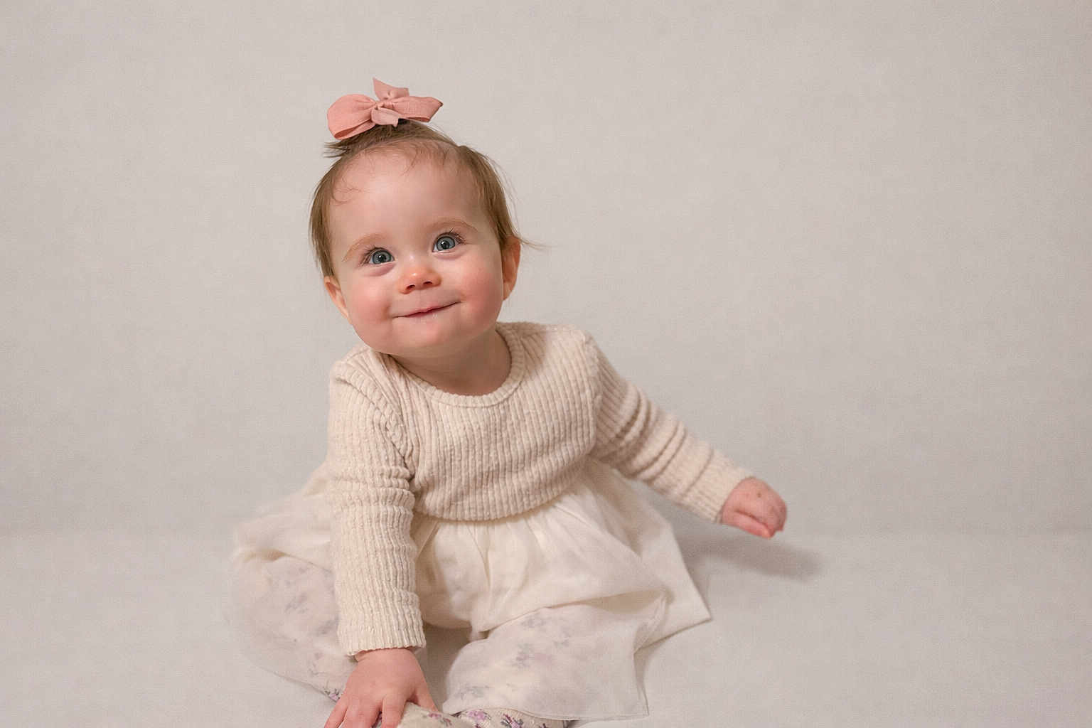 Louise a rejoint le concours — aidez-le/la à gagner de superbes lots ! baby, infant, toddler, bow_hair, pink_bow, cream_sweater, tulle_skirt, sitting, smile, rosy_cheeks, blue_eyes, portrait, studio, soft_lighting, neutral_background, cute, playful, indoor, fashion, child