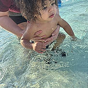 Ke-Von is registered to the contest to win money with this photo: child, toddler, water, splash, curly_hair, adult_hand, outdoor, play, summer, pool, sunlight, skin, person, water_splash, closeup, fun, care, nature, daylight, swimming
