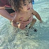child, toddler, water, splash, curly_hair, adult_hand, outdoor, play, summer, pool, sunlight, skin, person, water_splash, closeup, fun, care, nature, daylight, swimming