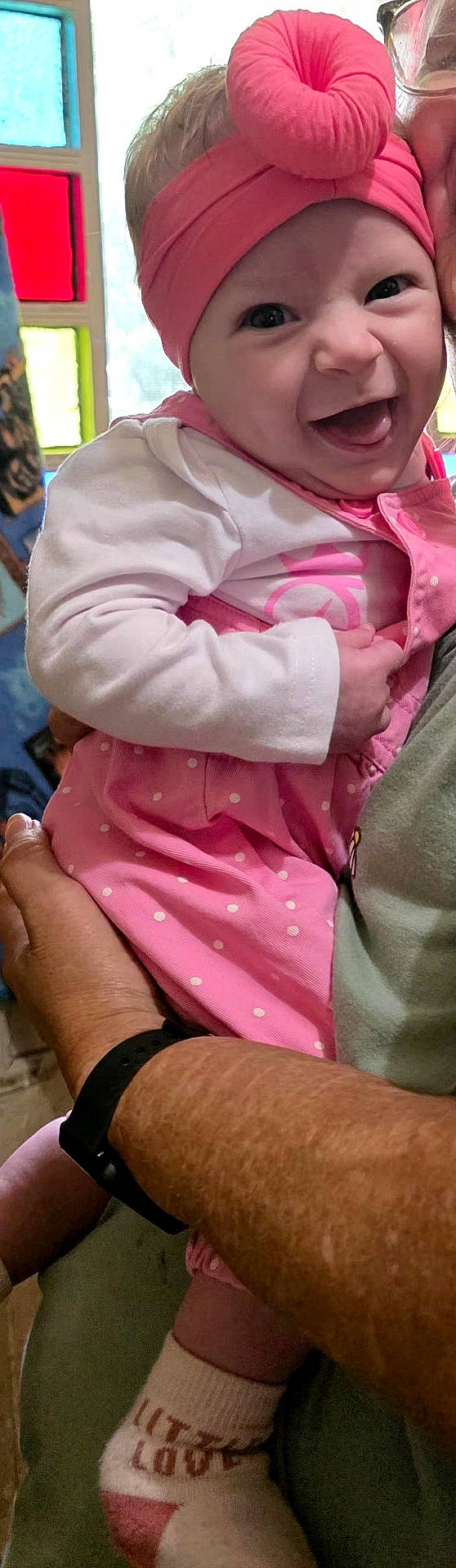 Jaceyn joined the competition — help win amazing prizes! adult_arm, baby, child, closeup, clothing, colorful_background, eyes, face, family, happy, headwrap, held, indoor, infant, pink_outfit, polka_dots, portrait, smiling, sock, turban